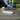 Person applying sealant to a driveway with a roller, with a car and house in the background.