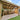 Wooden pergola structure in a backyard with patio and grass area.