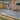 Paved patio area in front of a brick house with a garden bed.