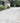 Paved driveway leading to a house with greenery and a car in the background; Dove Grey Limestone Block Paving