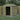 Wooden shed with a green roof, containing a lawnmower, surrounded by trees and a fence.