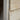 Close-up of a light natural wood plank or door panel with visible grain, edge profile, and a small dark screw head on a blurred background.