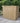 Wooden garden shed on a patio with greenery in the background