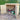 Wooden garden shed with a lawn mower and tools inside, set against a garden backdrop.