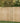 A light natural wood privacy fence installed outdoors on a grassy lawn with green trees in the background.