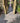 Outdoor pathway made of grey porcelain tiles with wooden gates on either side, leading to a grassy area.