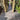 Outdoor pathway made of grey porcelain tiles with wooden gates on either side, leading to a grassy area.