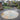 Round stone patio in a garden with a wooden shed and plants in the background