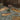 Decorative garden with rocks, logs, and small plants against a wooden wall.