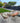 Outdoor patio area with wicker furniture and cushions in a garden setting.