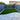 Backyard with artificial grass and stone patio area enclosed by blue fences.