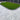 Artificial grass installed on a patio area with a fence and trees in the background.