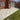 Paved patio area in front of a brick house with a grass lawn.